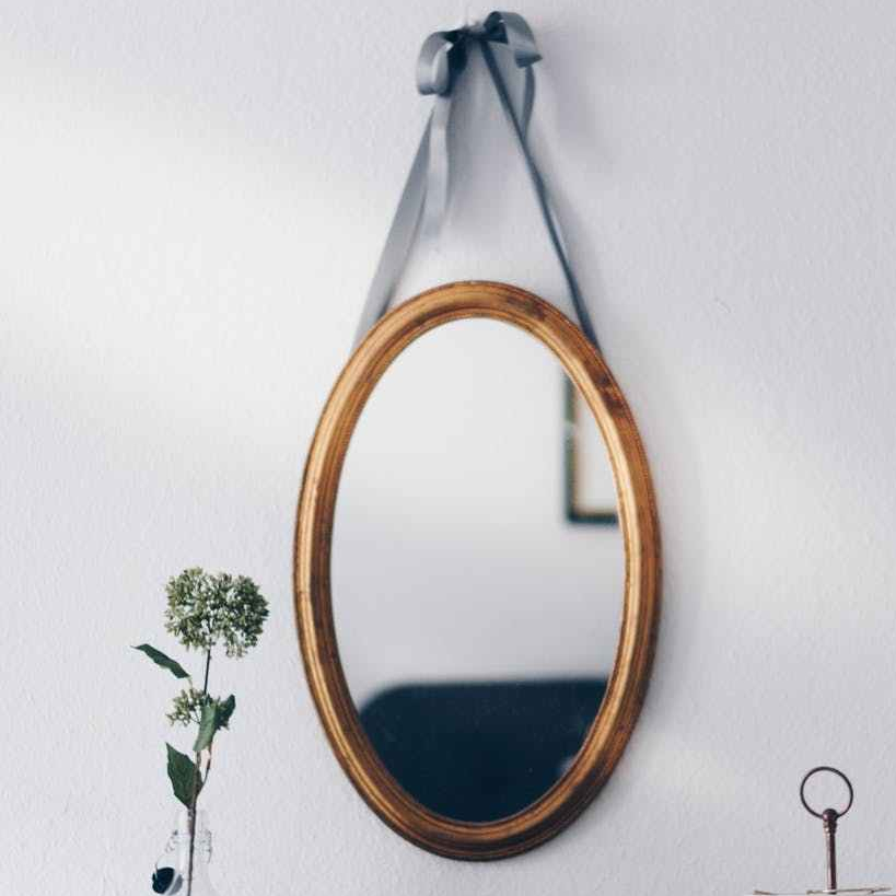 oval brown wooden framed hanging mirror